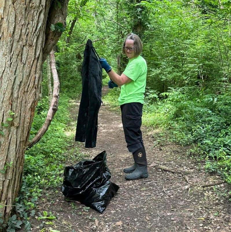 Swope volunteer collecting litter along a wooded trail