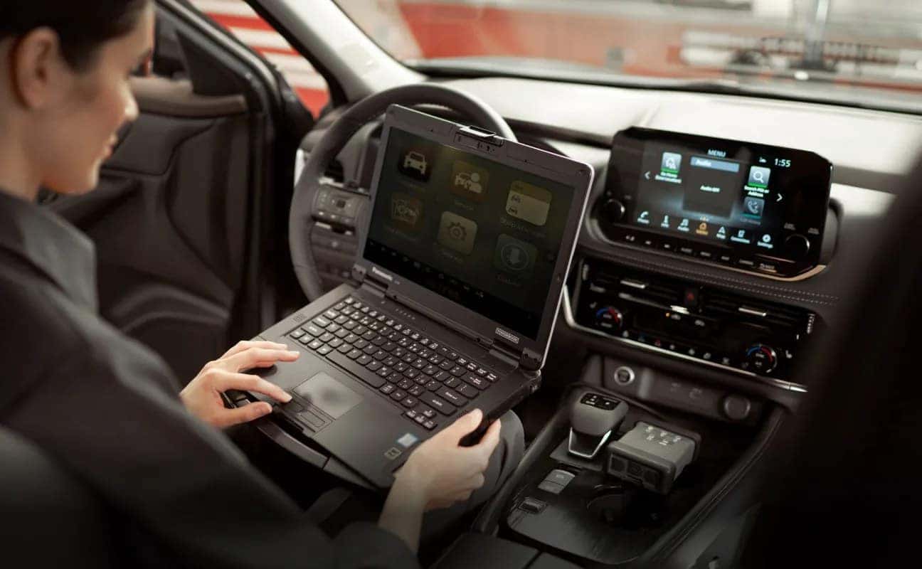 Nissan service technician using vehicle-specific diagnostic equipment inside a Nissan