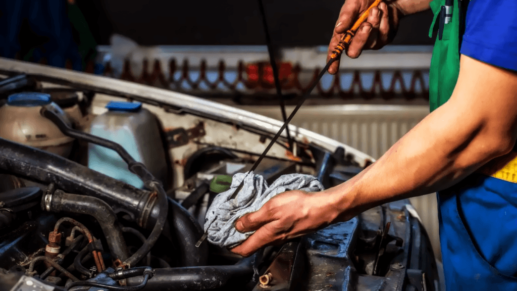 A technician checking a vehicle's engine oil