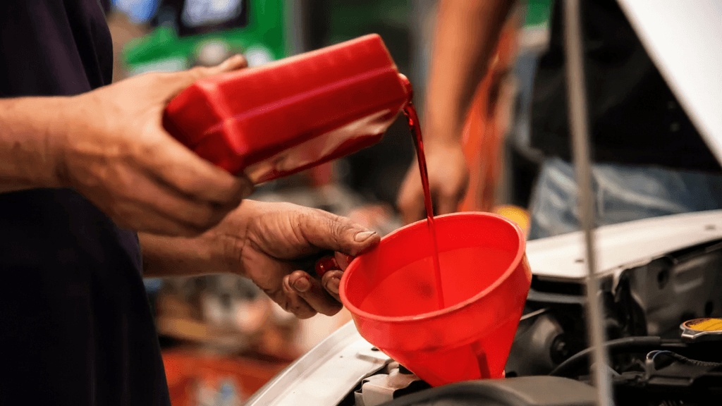 A technician pouring clean transmission fluid as part of a transmission fluid change