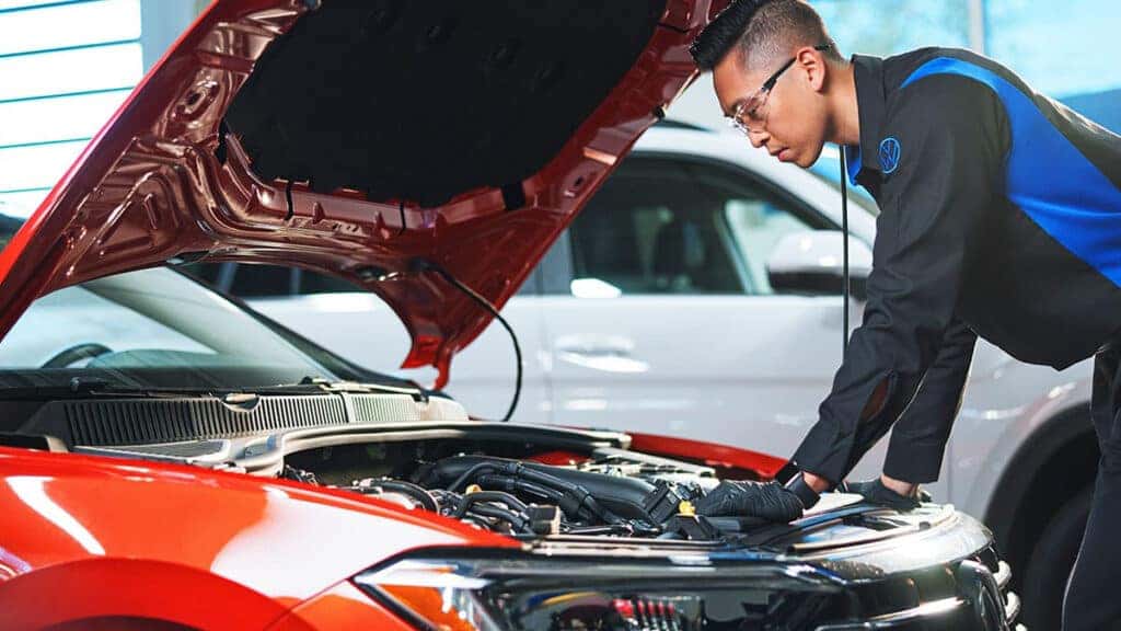 A Volkswagen technician inspecting a vehicle's engine