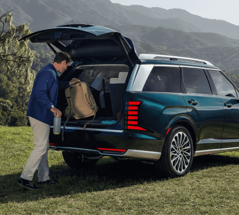 Man loading into a trunk of dark green Hyundai SUV