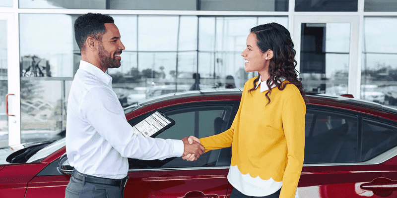 A car sales person showing customer a phone screen