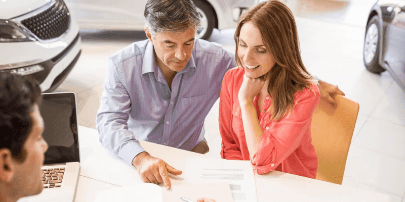 A car sales person showing customer a phone screen